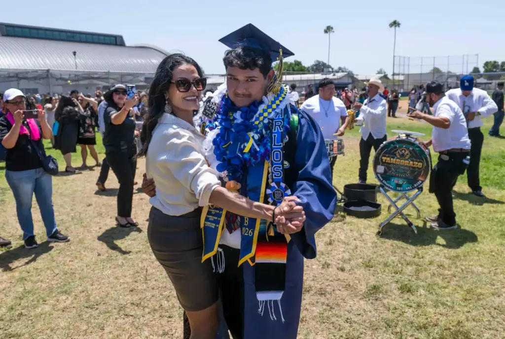 As banda group plays, graduate Carlos Ramirez dances with his...