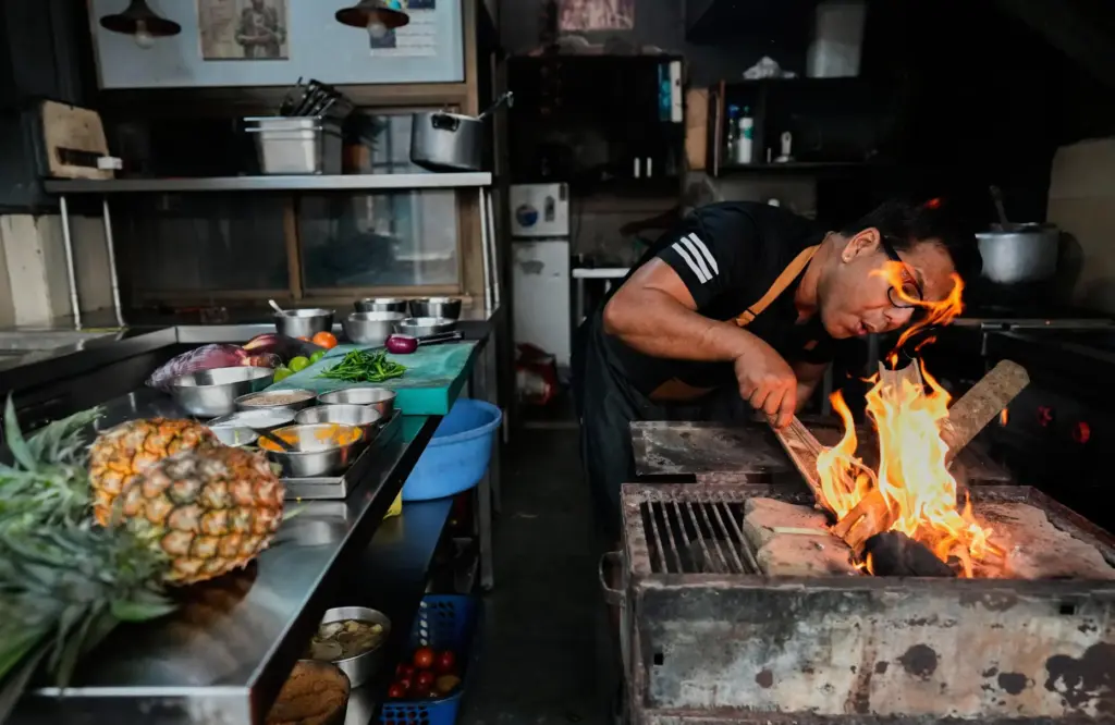chef lights a fire with wood and coal to prepare food