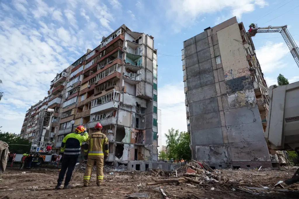 Rescue workers stand in the yard of an apartment building heavily damaged after a Russian strike.