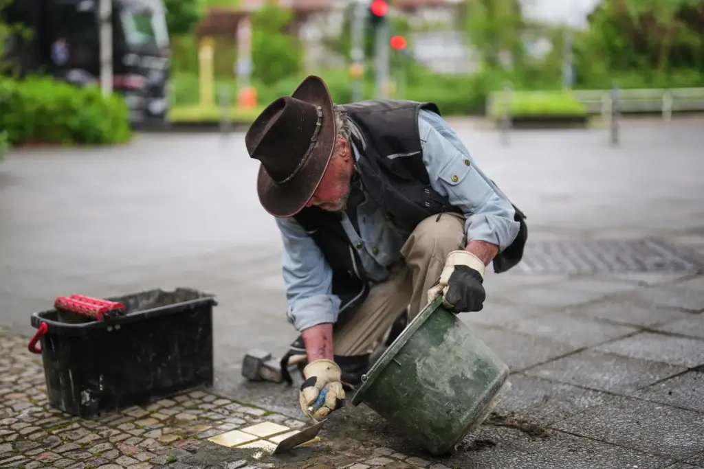 Artist Gunter Demnig places a palm-sized brass Holocaust plaques