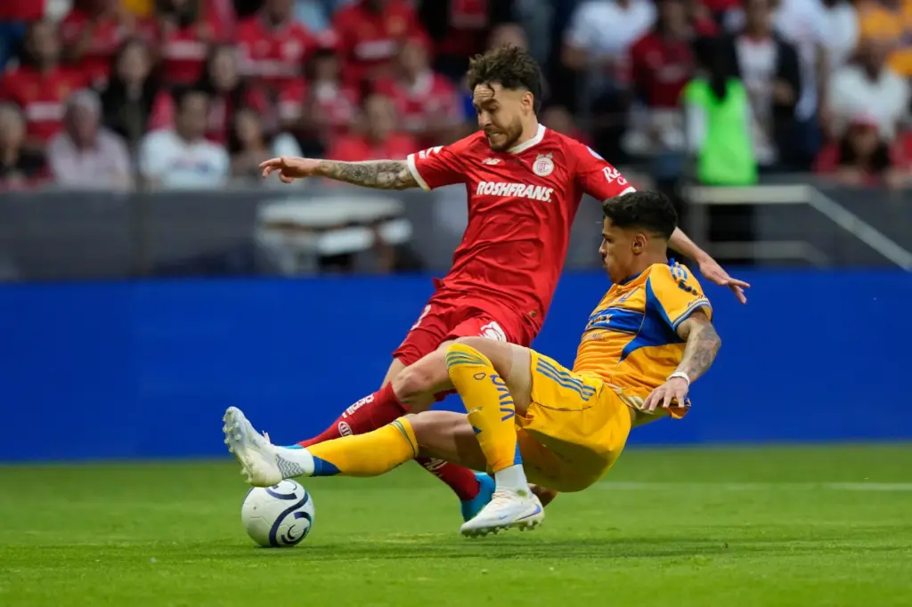 Tigres’ Romulo, bottom, challenges Toluca’s Jesus Angulo during the CONCACAF...