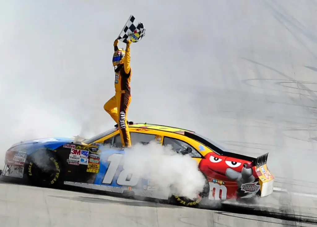 Kyle Busch celebrates his win in the NASCAR Sprint Cup Series' Autism Speaks 400 auto race.