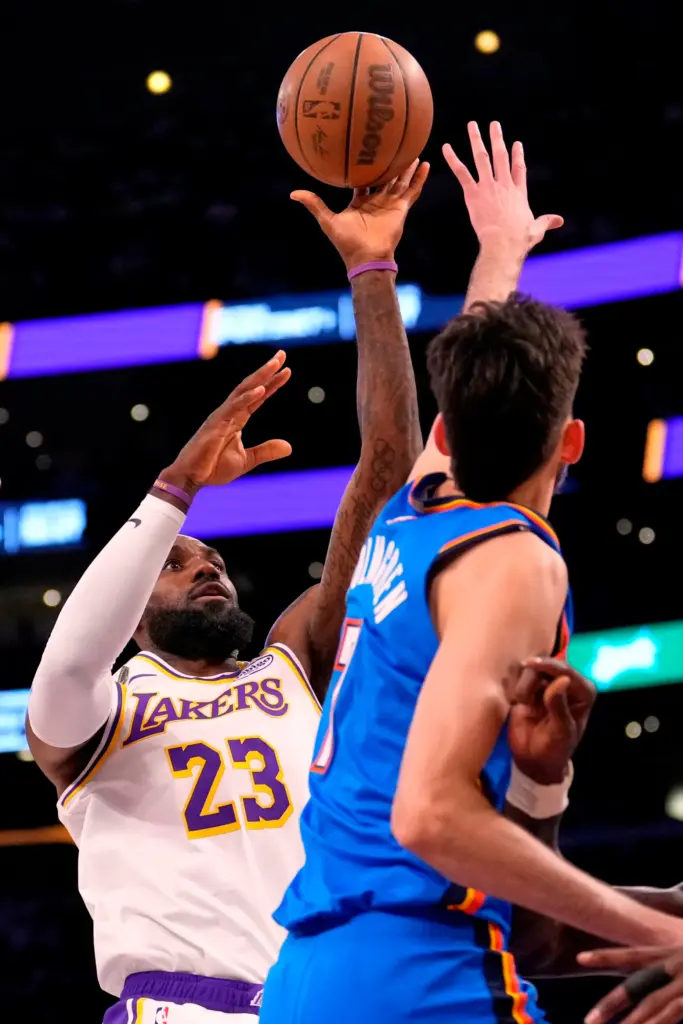 Lakers star LeBron James, left, shoots as Oklahoma City Thunder...