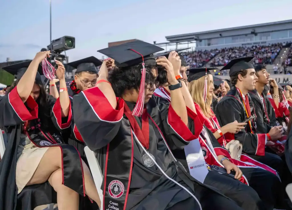 Graduates turn their tassels from right to left as they...