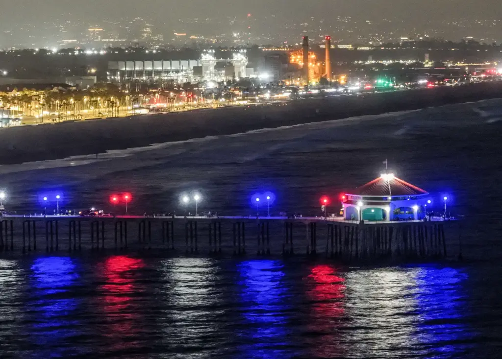 The Huntington Beach Pier is lit in red, white and...