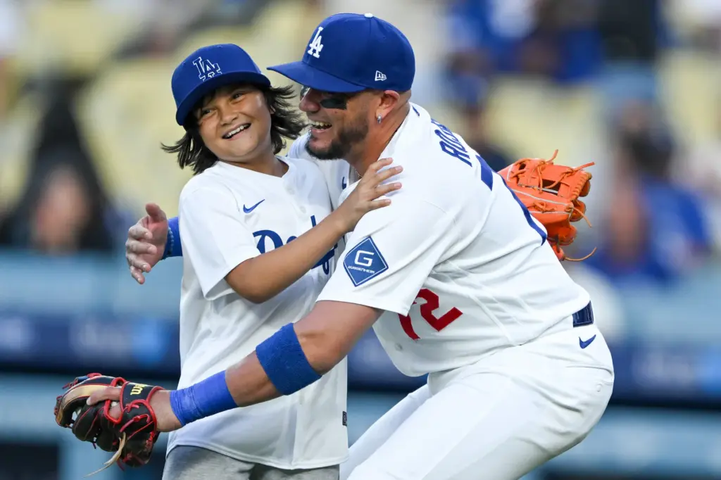 Dodgers infielder Miguel Rojas greets his son after he threw...