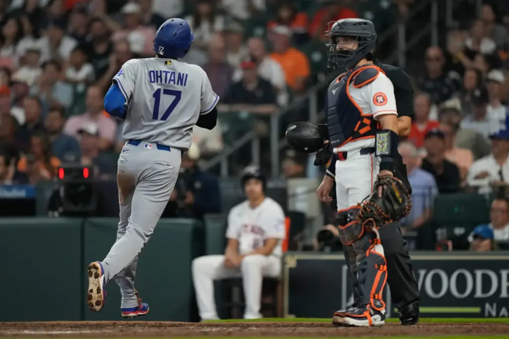 Dodgers star Shohei Ohtani, left, scores during the fourth inning...
