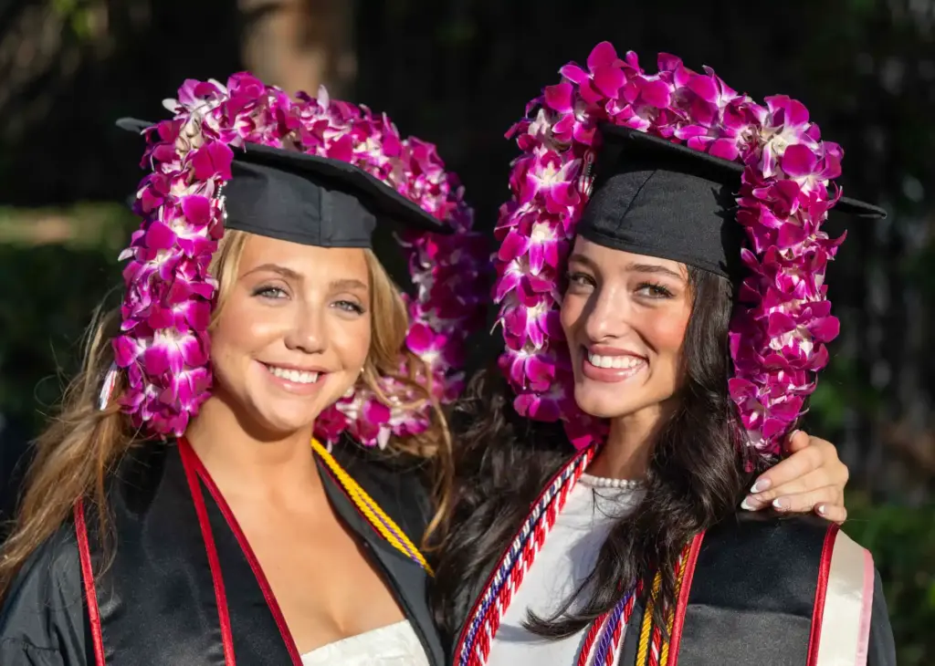 Friends Abbey Werner, left, and Braylan Enscoe jokingly wear leis...