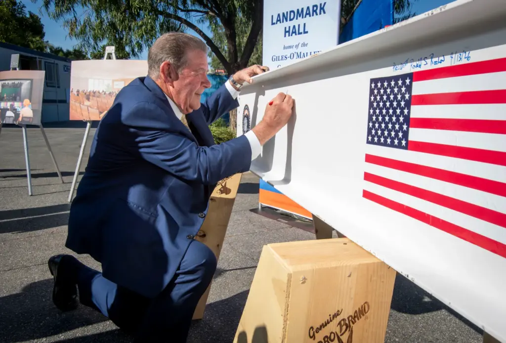 Terry M. Giles signs his name on a beam to...