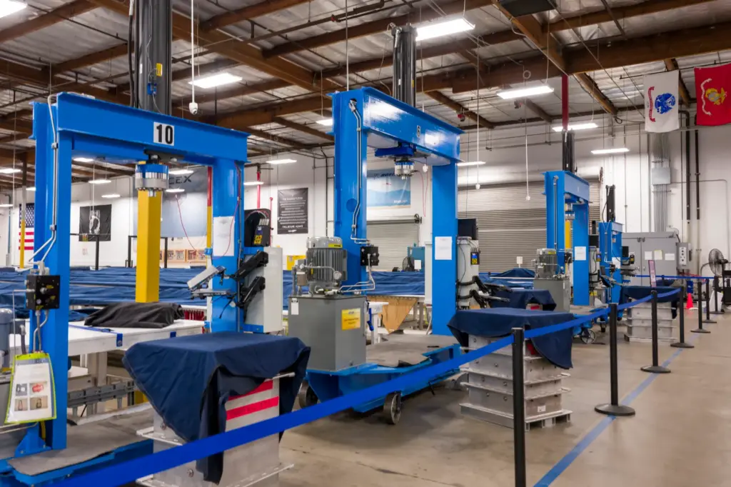 Giant blue steel frames support the hydraulic presses that compress...