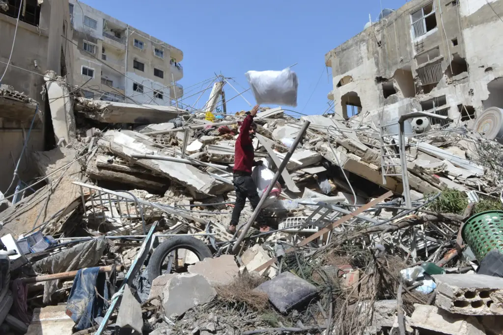 A man collects his family’s belongings from the rubble of...