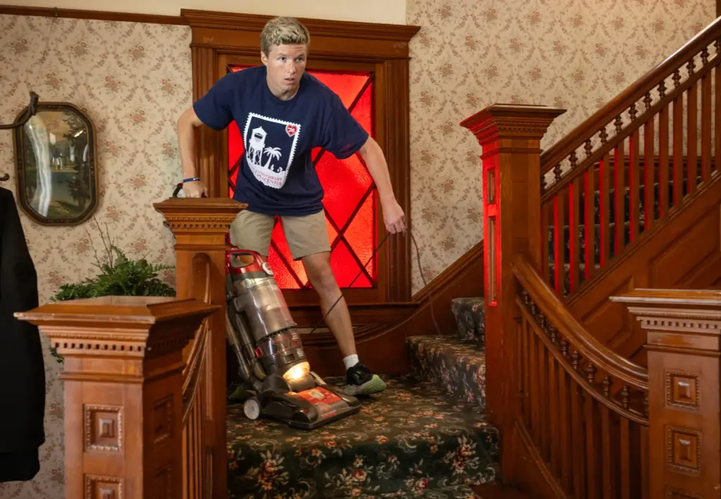 Tyler Shultz vacuums the stairs inside the historic Bradford House...
