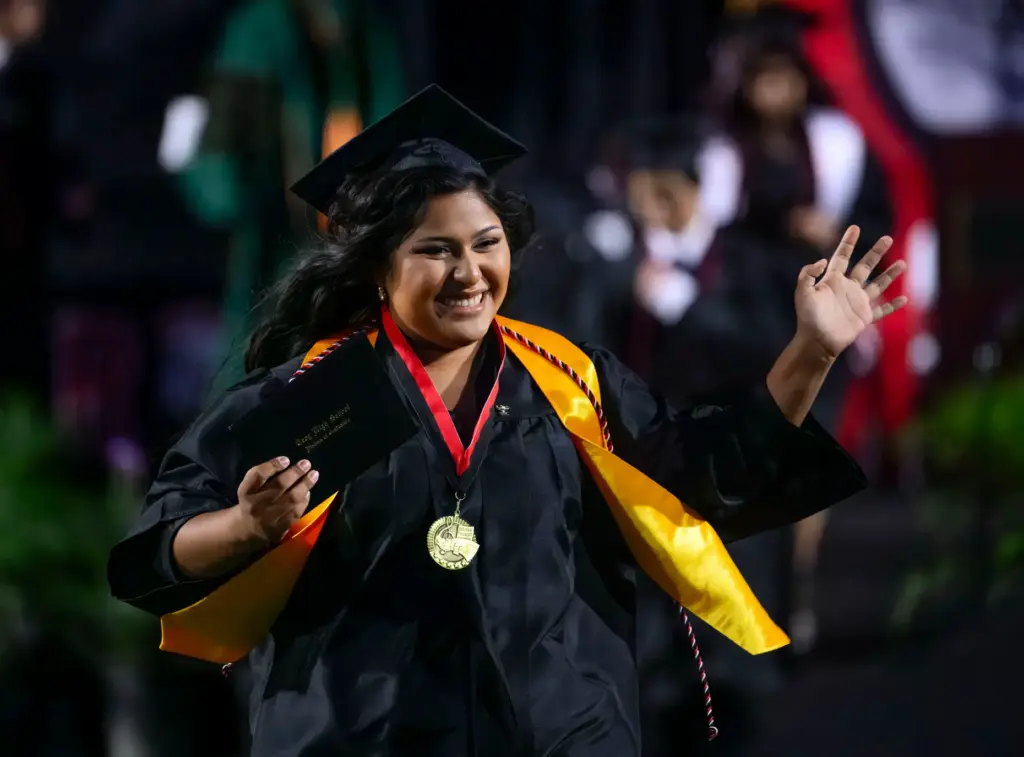 A happy graduate runs off the stage after receiving her...