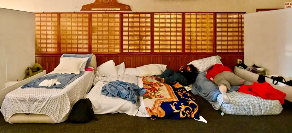 Evacuees Kylie Romero hangs out on a cot next to...