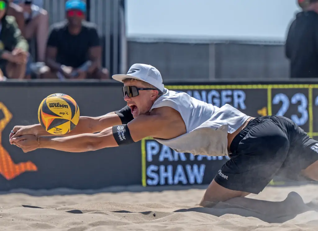 Miles Partain dives in the sand to dig the ball,...