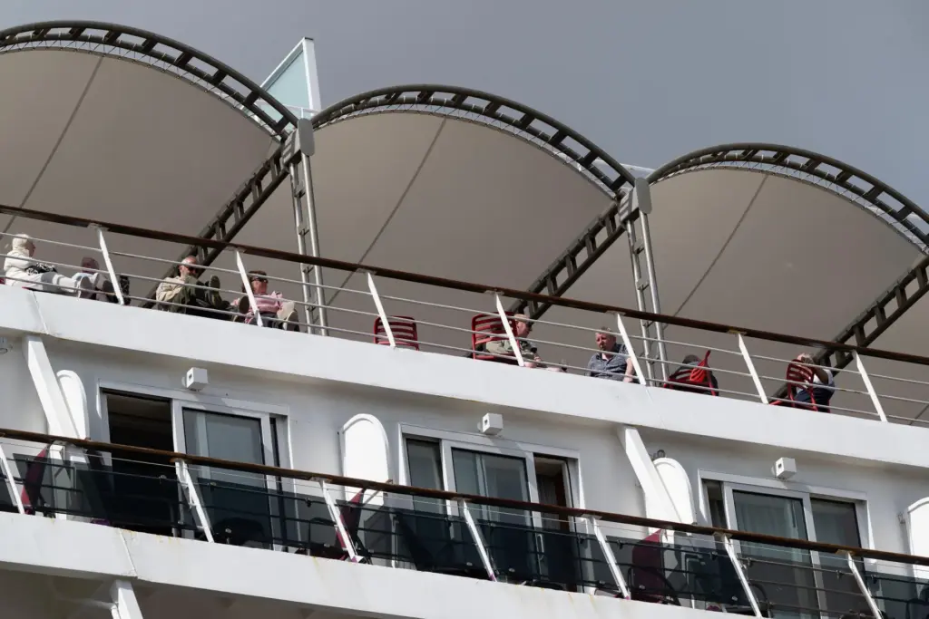Passengers stand aboard the British cruise ship Ambition, as French...