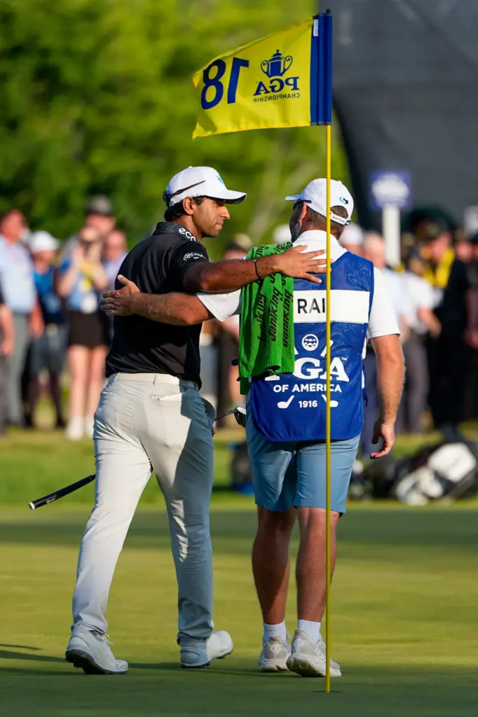Aaron Rai, of England, hugs his caddie after his round...