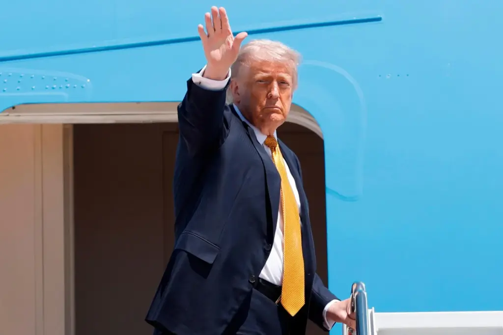 President Donald Trump waves from the stairs of Air Force...