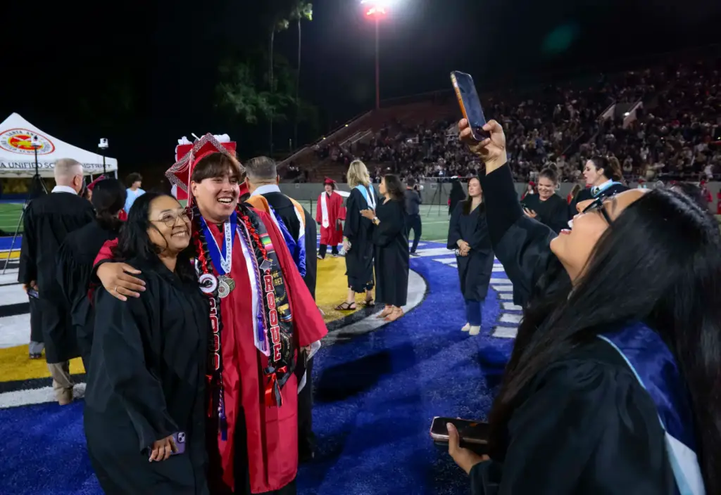 Graduate Roque Ramirez gets his photo taken with a teacher...
