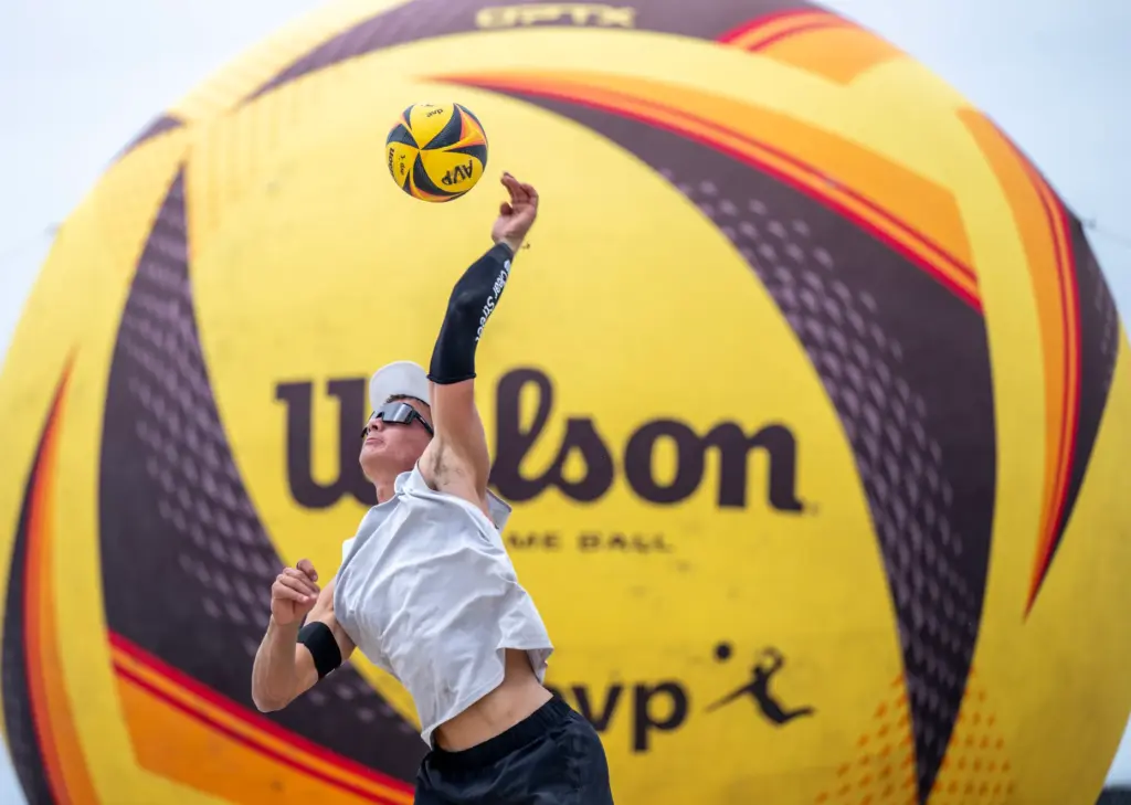 Miles Partain does a jump serve while playing with teammate...