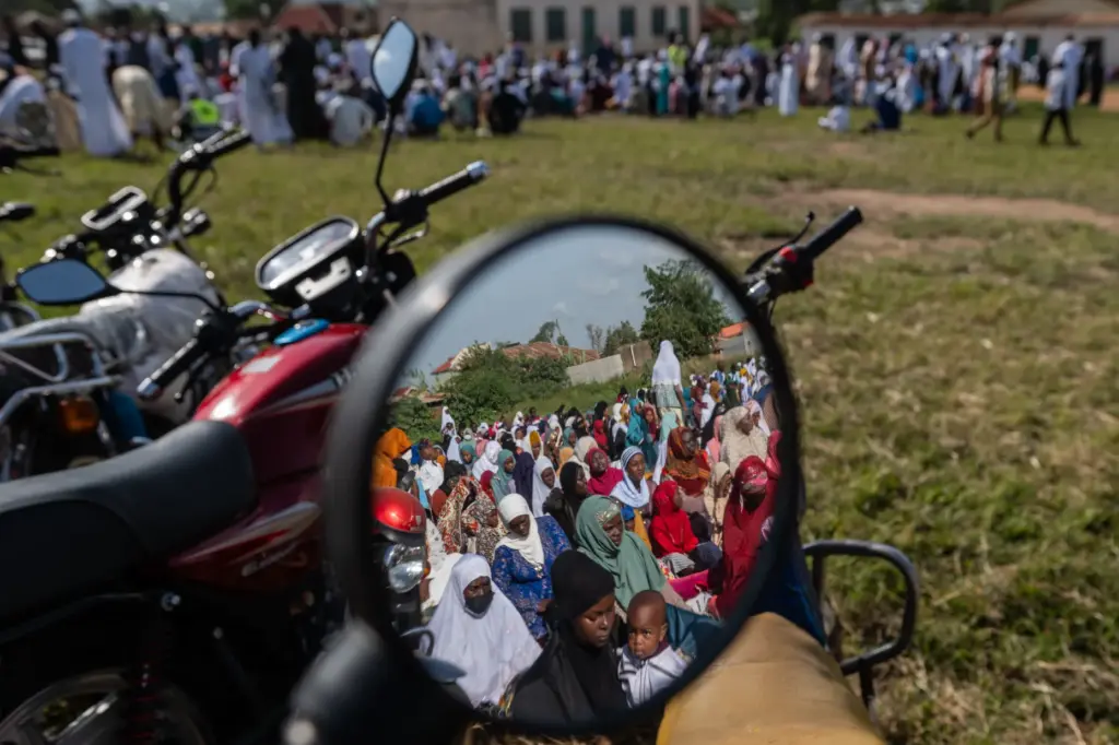 Muslims are reflected in a motorcycle mirror as they gather to pray.