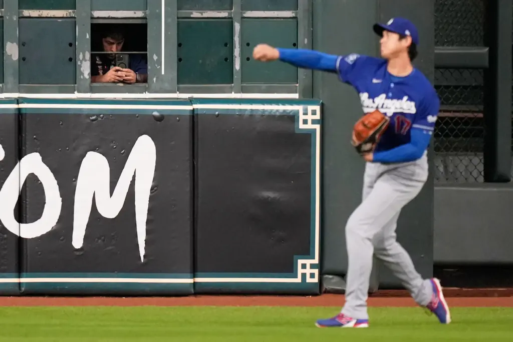 A worker takes photos as Dodgers starting pitcher Shohei Ohtani...