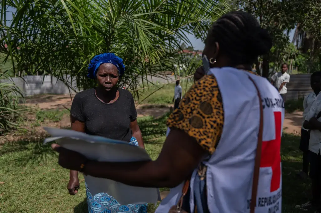 Vanny Birungi, a Red Cross volunteer, speaks to a woman