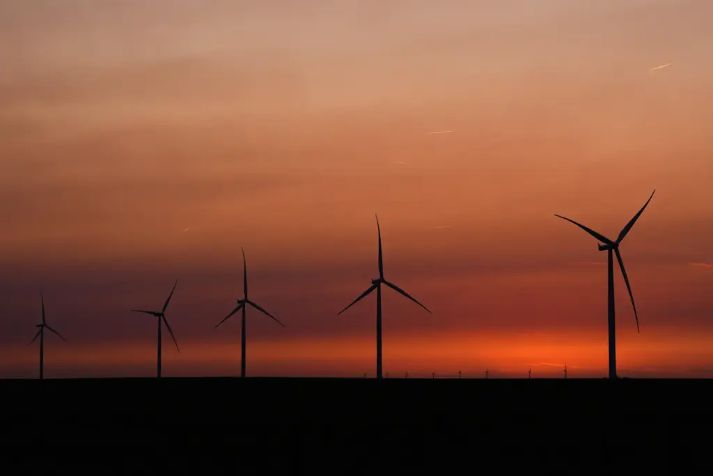 Wind turbines are silhouetted against the sky at dusk
