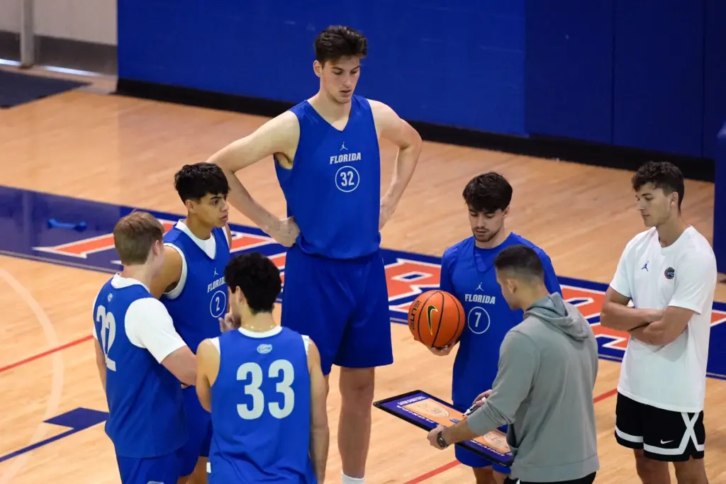 Florida’s 7-foot-9 Olivier Rioux, back center, gathers with coaches and...