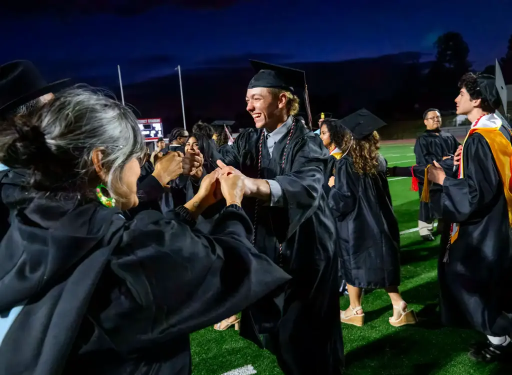 Graduate Mason Avey is congratulated by a teacher following the...