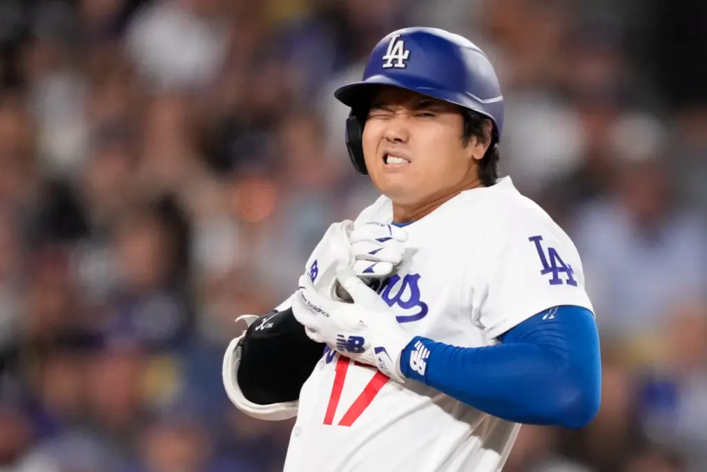 Dodgers star Shohei Ohtani reacts after being hit by a...