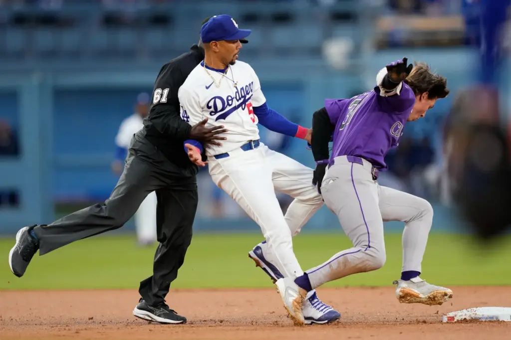 The Colorado Rockies’ Jake McCarthy, right, loses his balance after...