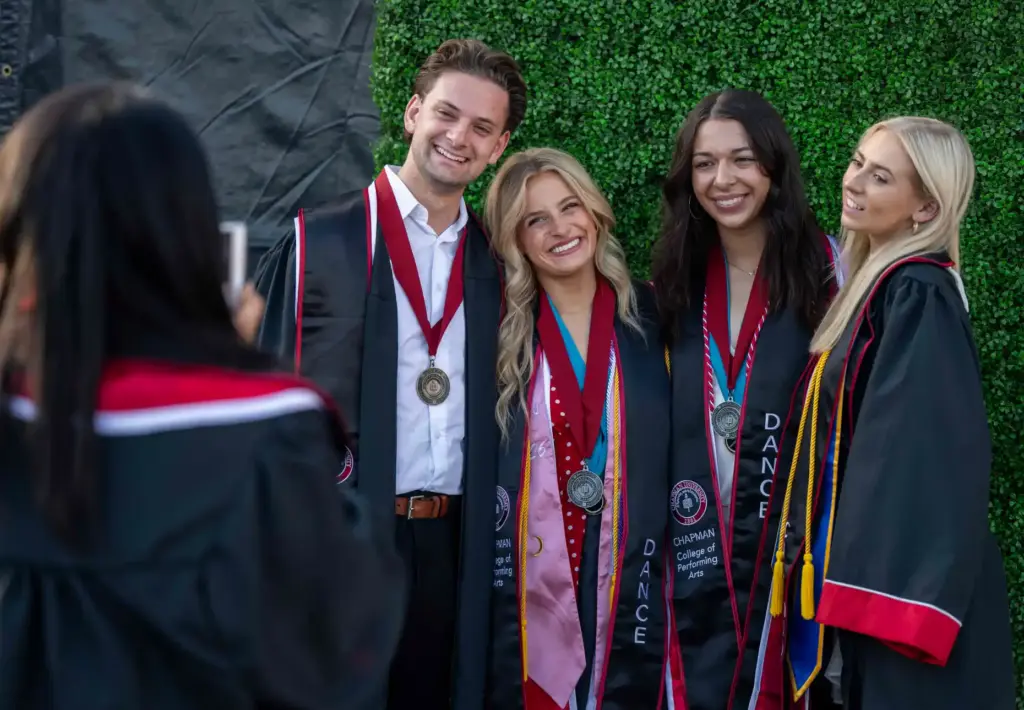 Friends pose for photos in their graduation regalia before the...