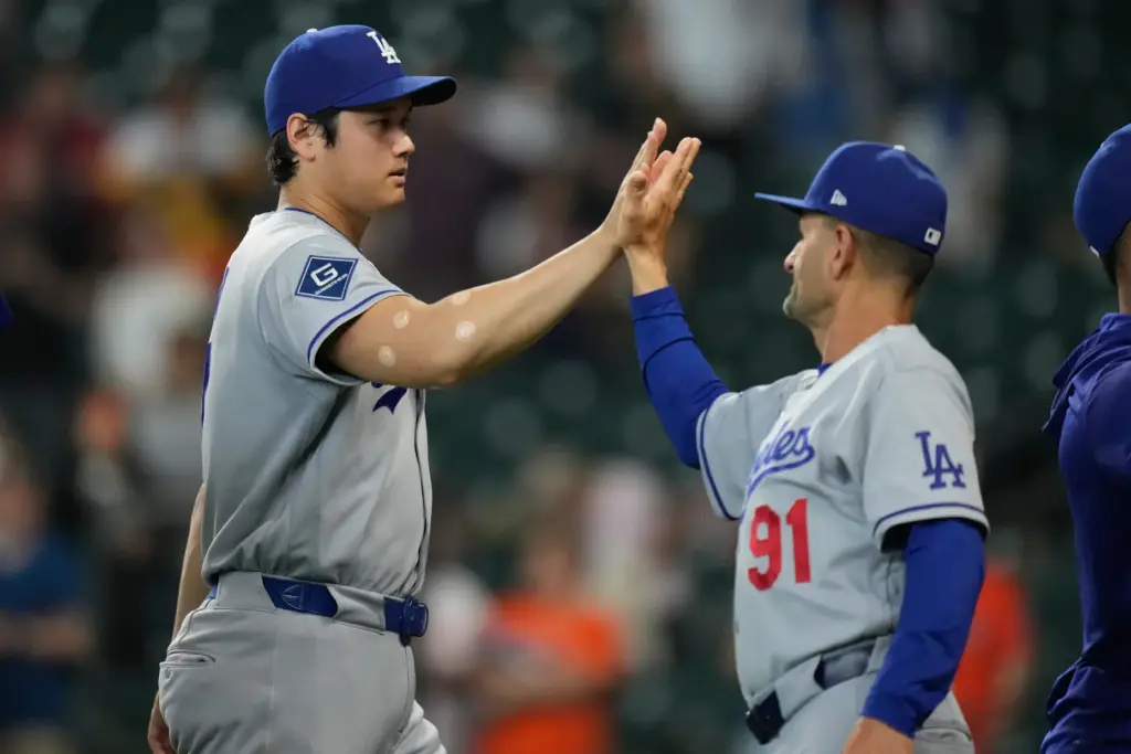 Dodgers star Shohei Ohtani, left, celebrates with third base coach/outfield...