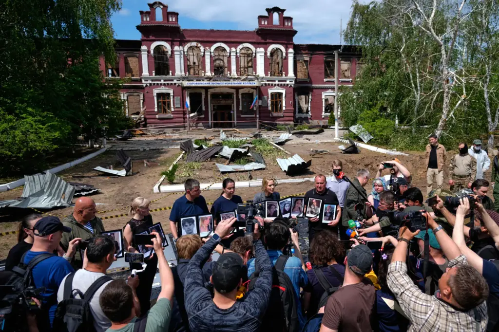 Russia's Commissioner for Human Rights Yana Lantratova stands by citizens holding portraits of what they say were victims of a Ukrainian drone strike.