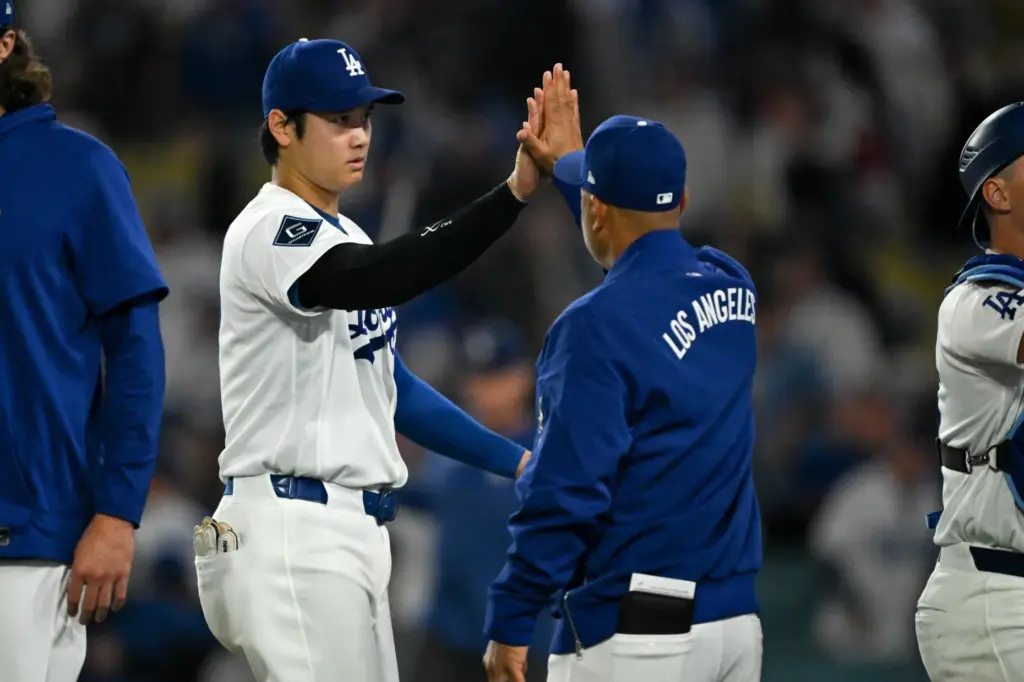 Dodgers star Shohei Ohtani, left, high-fives Manager Dave Roberts after...