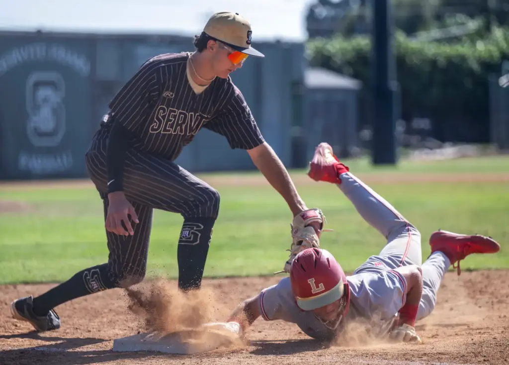 Orange Lutheran infielder Jordan Kurz dives safely back to first...