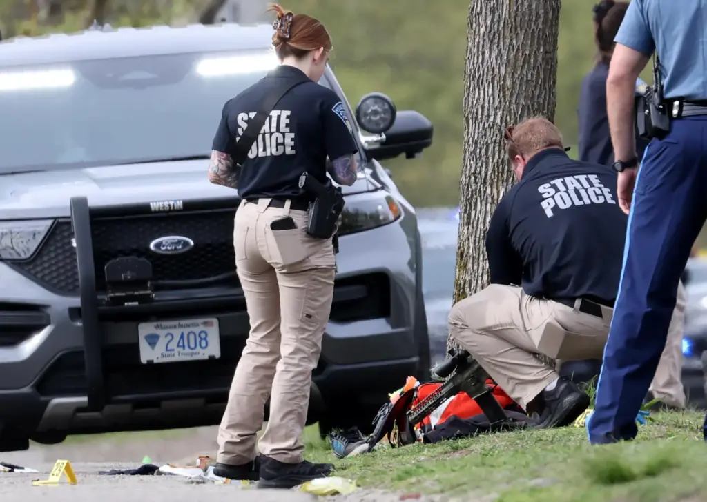A member of the State Police bends to pick up...