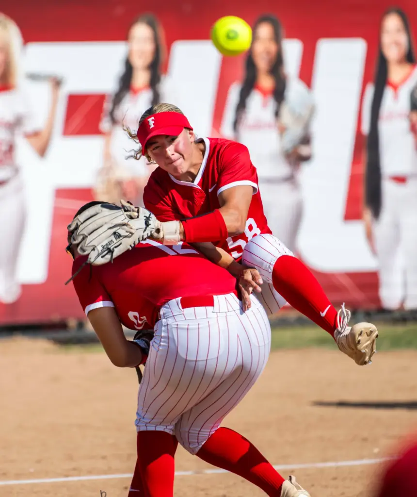 Fullerton shortstop Soleil Luna collides with third baseman Ava Flores...