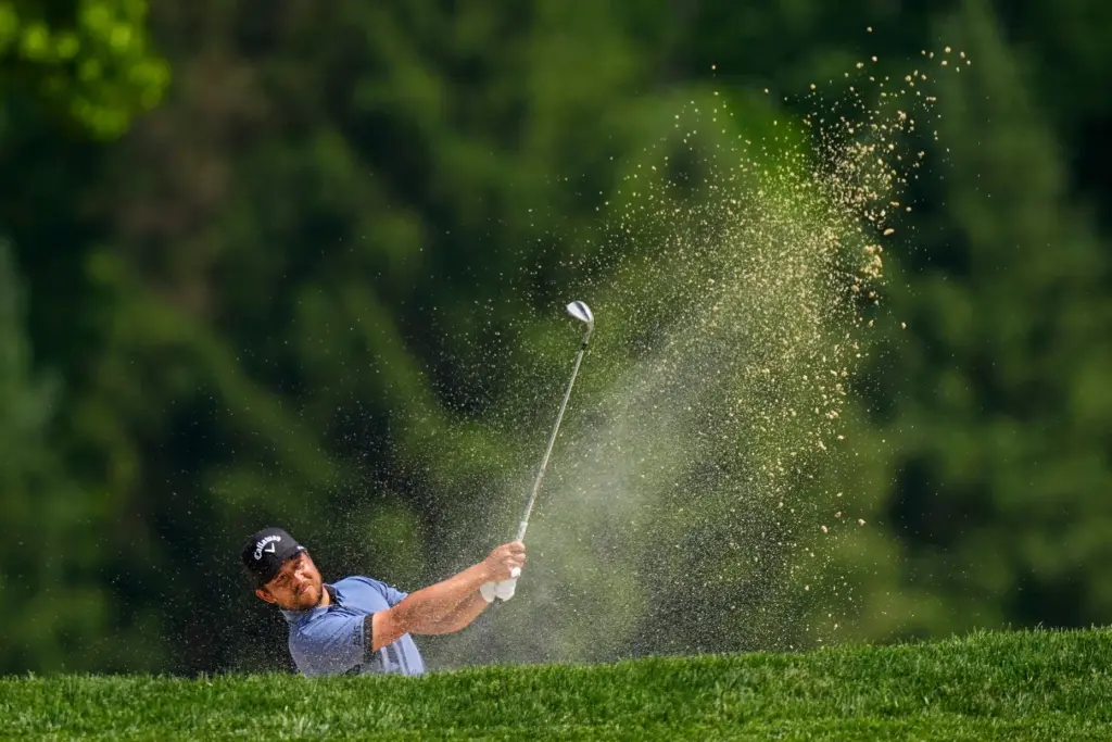 Xander Schauffele hits from the bunker on the second hole...