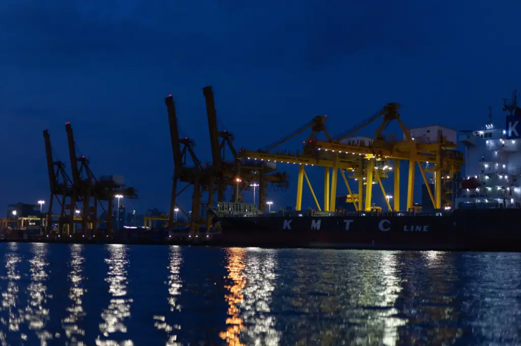 Night lights from Khlong Toei Pier shimmer on the Chao Phraya River in Bangkok.