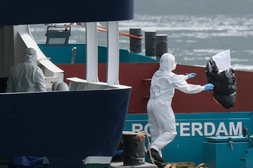 People in protective gear remove waste from the MV Hondius cruise ship