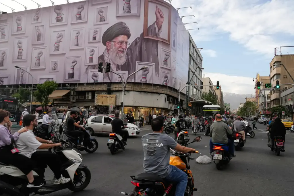 Motorbikes drive past a billboard with graphic showing the late...