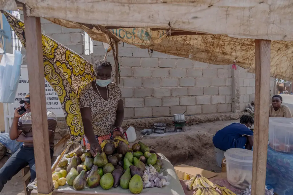 A woman wearing a protective mask sells fruit from a roadside stall in Bunia, Congo.