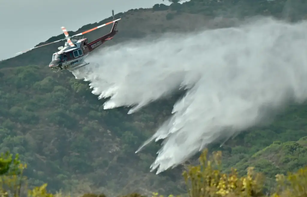 An OCFA helicopter demonstrates a water drop after sucking up...