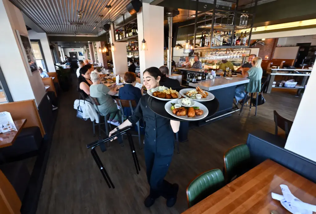 Server Ashlee Dorantes delivers food at Market Broiler’s Fish House...