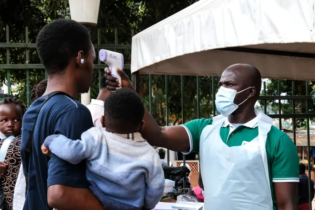 A health official uses a thermometer to screen people in...