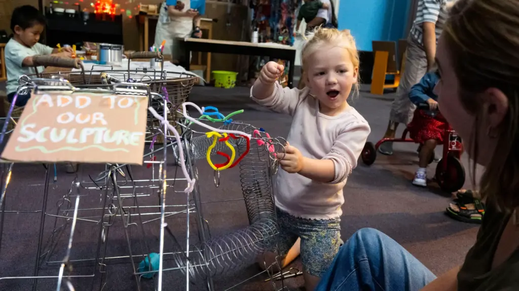 Harper Steen, 3, adds to a group sculpture during opening...