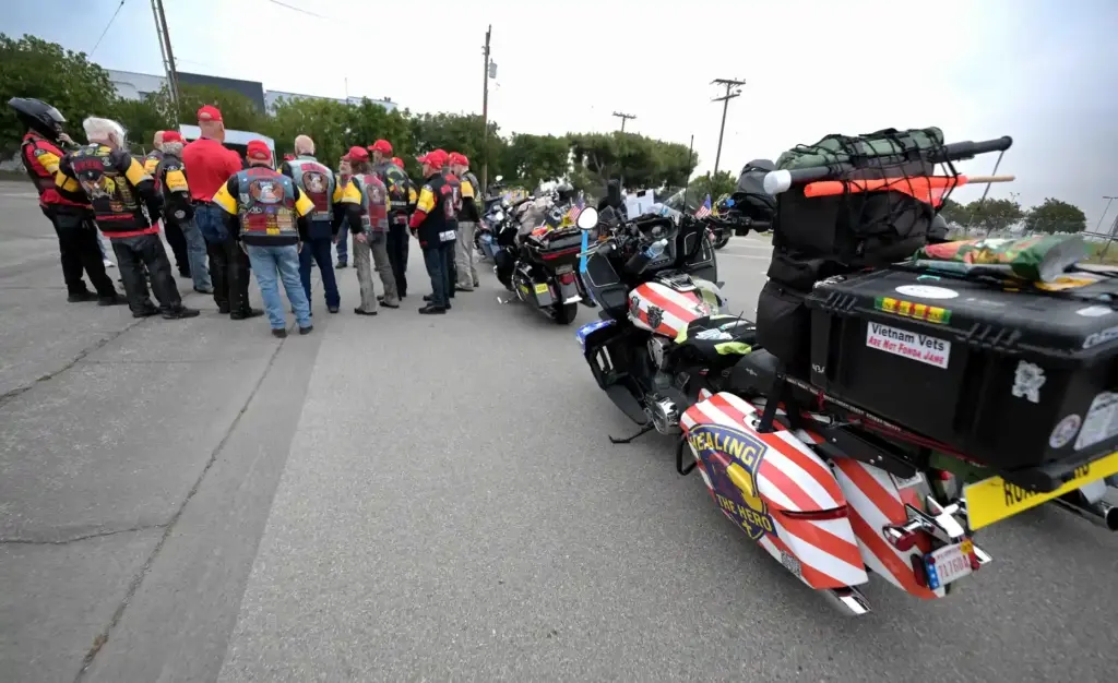 Riders gather near their motorcycles as they prepare to take...