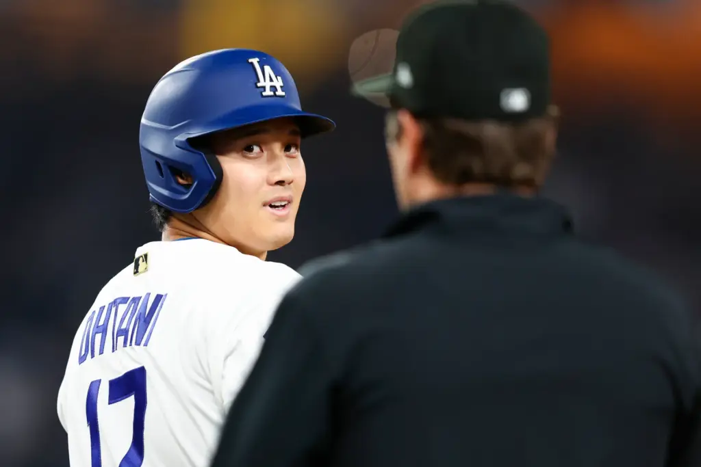 Dodgers star Shohei Ohtani, left, reacts toward the first base...